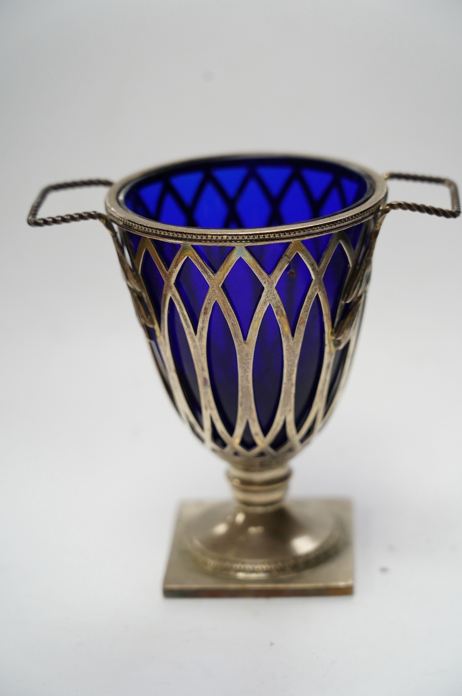 An Edwardian repousse silver porringer, Daniel & John Welby, London, 1905, height 73mm, together with a late Victorian silver two handled sugar vase with blue glass liner, London, 1895. Condition - fair